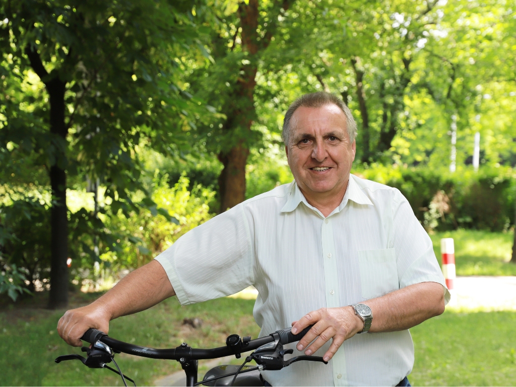 Pan Andrzej z Warszawy prowadzi rower w parku