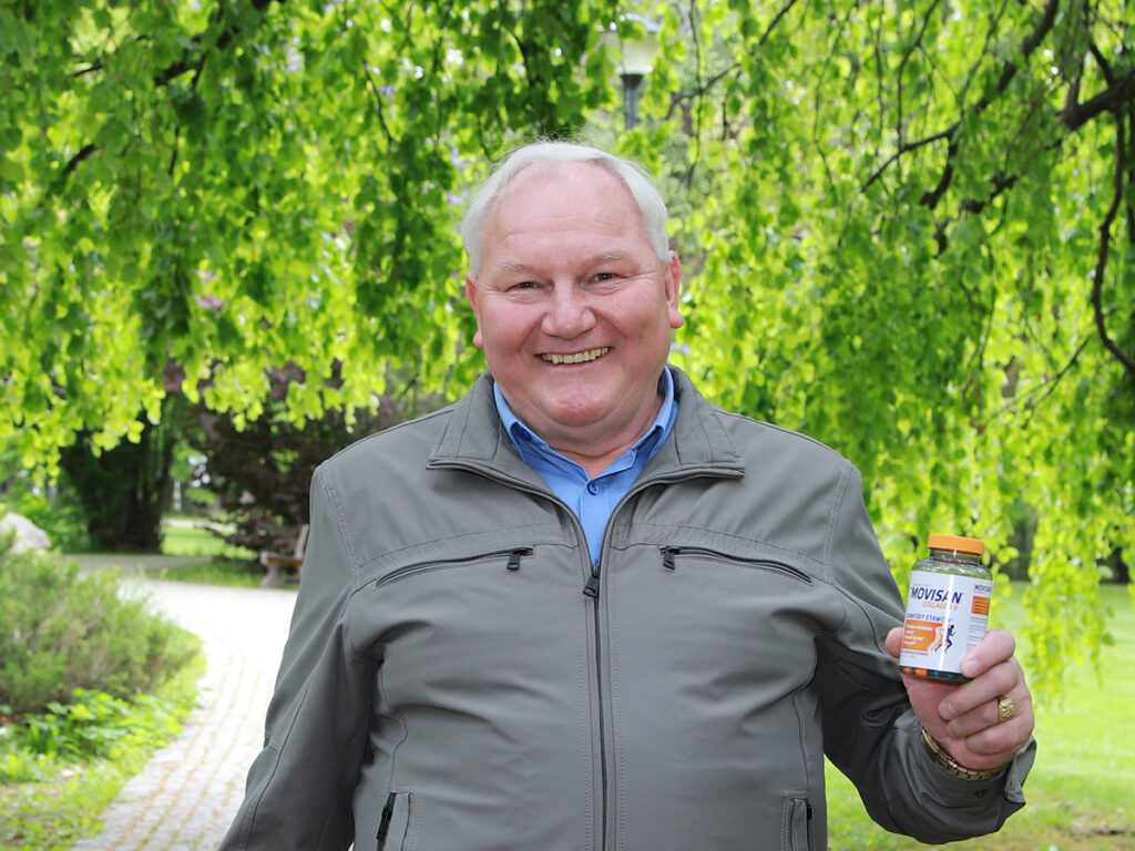 Pan Robert pozuje z Movisanem w ręce na tle zieleni w parku.