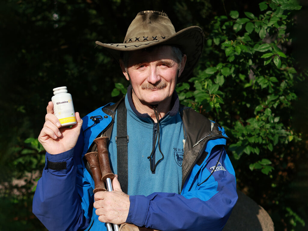 Pan Zbigniew pozuje w kapeluszu kowbojskim, trzymając opakowanie witaminy C w ręce.