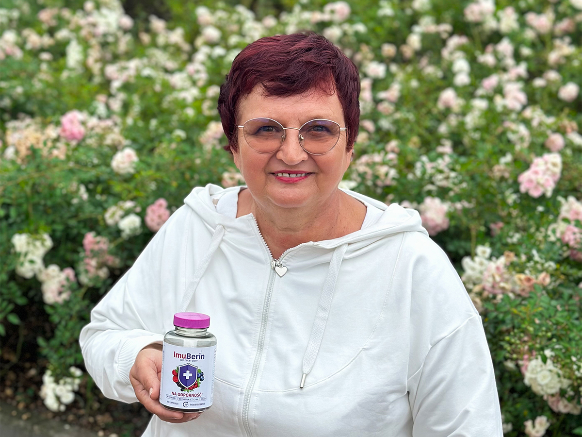 Naturalne wsparcie odporności z Norwegii Pani Elżbieta pozuje z suplementem diety Imuberin na tle krzaku róż